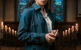 A woman holds a notebook in a church with candles