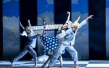 Dancers raise their arms in front of a street sign