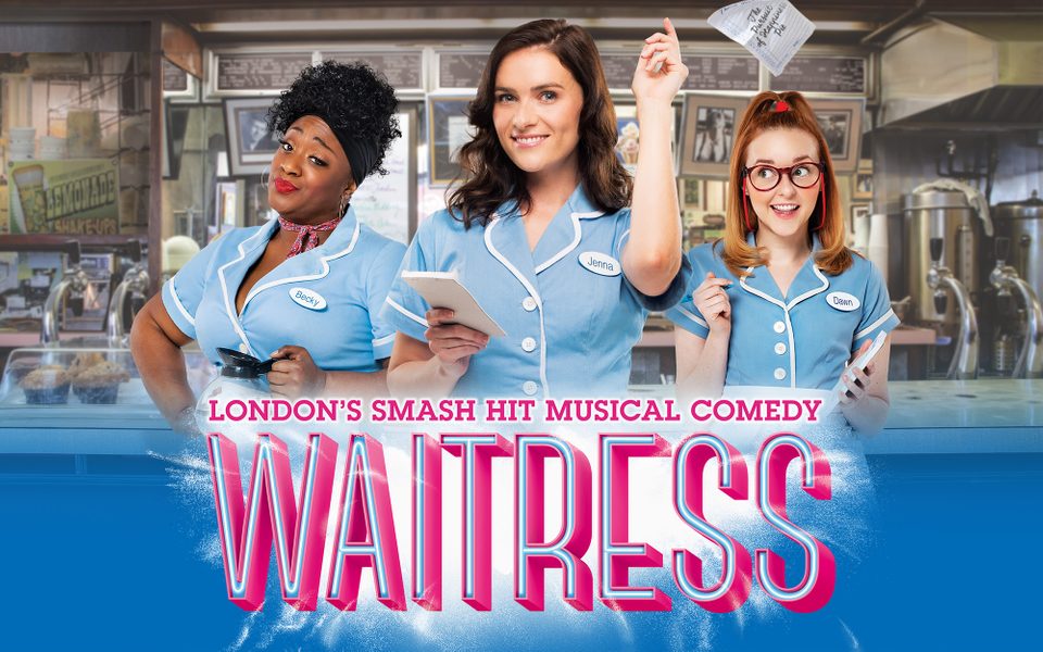 3 cast members pose as waitresses in light blue dresses and aprons against a café backdrop