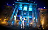 A performer on stilts stands in front of the theatre