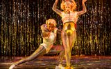 Two women in outrageous gold costumes strike dramatic poses