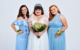 A happy bride stands between two bridesmaids