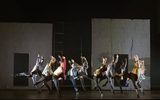 A group of dancers with their arms raised and one leg raised to the side