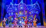 Seven dwarfs stand in front of a cottage