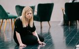 A forlorn looking woman sits alone on the floor