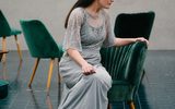 A pensive looking woman sits alone on a green chair lost in her thoughts