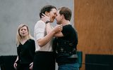 A man and a woman almost share a kiss as a distressed woman looks on