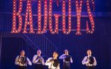 A group of boys dressed in top hat and tails perform a routine on stage