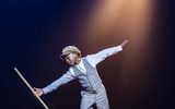 A young boy performs a dance with a mop