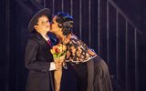 A boy holding a bunch of tulips gets a kiss on the cheek from a girl