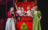 A fgroup of five women stand in and around a big red garbage bin; the three women in the bin are holding a variety of musical instruments