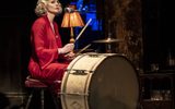 A woman sits behind a set of drums