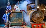 Two children are surprised by the 'Demon Dentist' character who appears out of a truck being pulled along by an old fashioned steam train
