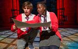 A boy and girl wearing red school cardigans look surprised by something they see on a map