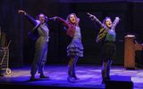 Three young women strike a dramatic pose on stage