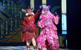 Two females dressed as a cat and a fox. They have pink and red costumes with lots of mismatched fabrics.