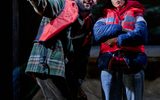 A man and woman wearing life jackets. The woman looks as the man is pointing something out to her.