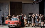 A group of people all crowding around a car.