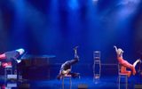 Three women, all balancing on chairs with their feet in the air.