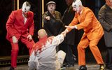 Three cast members point at a person on the floor, the are wearing white and appear to be covered in blood.