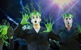 People dressed in black with greenery growing from their heads and fingers.