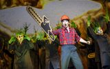 A person carrying a cardboard chainsaw stands in front of people dressed as trees.