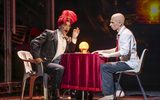 A person dressed plainly sits opposite a fortune teller.