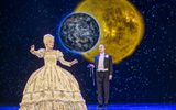 A lady wearing a large golden dress sings.