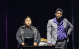 A female holding a clip board looks concerned whilst a male in a suit beside her looks pensive.