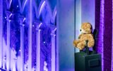 A teddy bear is set up at the side of the stage to watch over the children.