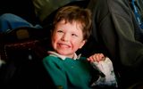 A boy is smiling and holding a packet of crisps.