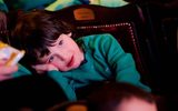 A boy leans his head to the side while watching the stage,