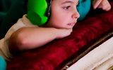 A boy gazes over the balcony wearing ear defenders.