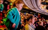 A young girl stands at her seat.