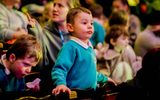 A young boy stands at his seat.