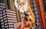 A man dressed as a giraffe wears a cone and is in a wheelchair