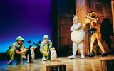 Two penguin puppets and a woman dressed as a hippo and man dressed as a giraffe.