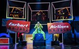 A woman in an all green flying suit sitting on boxes on the stage.