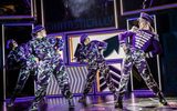 Three women in camouflage outfits dancing.