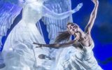 A woman dances in front of an ice sculpture of an angel.