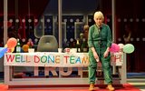 A female looks exhausted sitting next to a banner reading 'Well Done Team'.