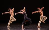 Three dancers standing on one leg, leaning backwards with their arms stretched behind them.