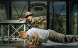 One man in military uniform shouts at another doing press ups on the floor.