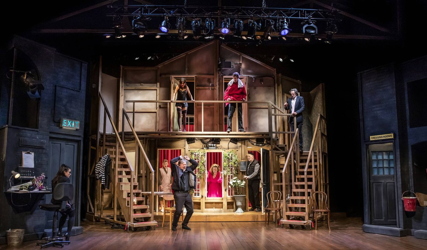 Photo of stage from Noises Off which looks like a house and 8 actors on stage