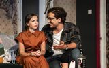 A man and woman talk while sitting on a sofa.