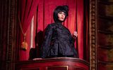 A female standing in a theatre box looking pensive.