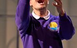 A boy in school uniform raises a ball in the air.