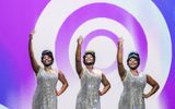 Three women dance with silver sequined dresses on.