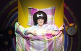A person lying in bed with their flowery pyjamas on.