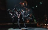 Three male dancers balance on one leg.